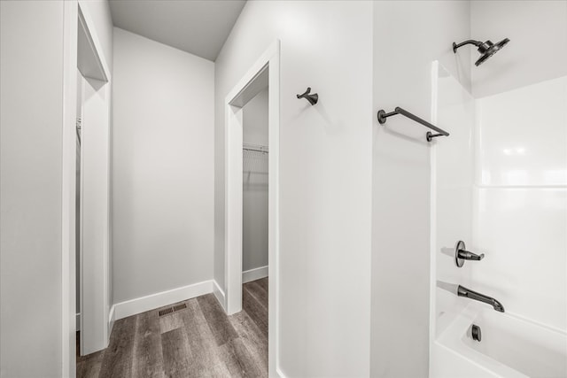 full bath with bathtub / shower combination, visible vents, a spacious closet, wood finished floors, and baseboards