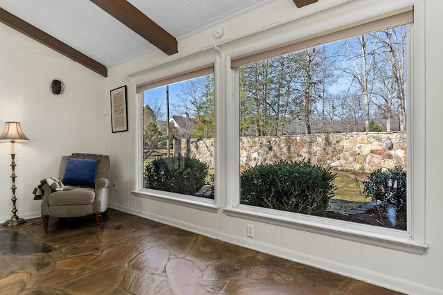 living area featuring vaulted ceiling with beams and baseboards