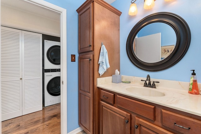 bathroom with vanity, stacked washer / dryer, and wood finished floors