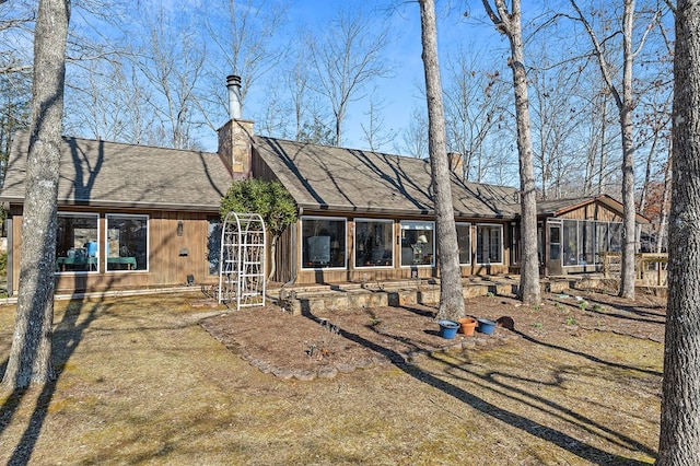 back of property featuring a shingled roof, a chimney, and a sunroom