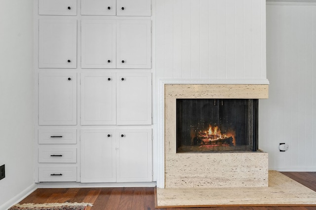 details with a lit fireplace, baseboards, and wood finished floors