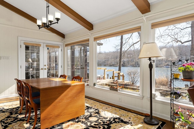 sunroom featuring french doors, a water view, a notable chandelier, and lofted ceiling with beams