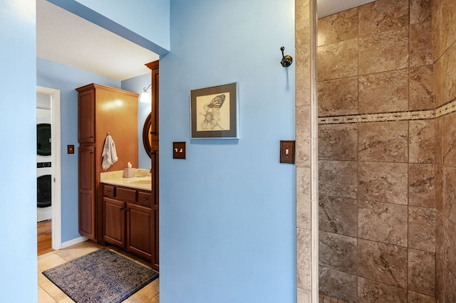 bathroom with tiled shower, tile patterned flooring, and vanity