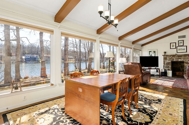 dining space with vaulted ceiling with beams, a chandelier, a fireplace, wood finished floors, and visible vents