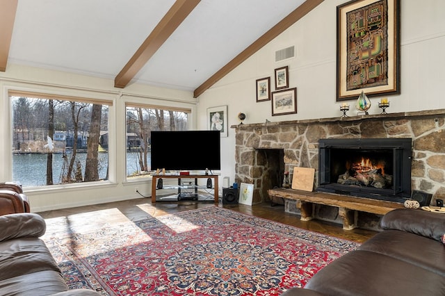 living area featuring visible vents, beamed ceiling, wood finished floors, a stone fireplace, and high vaulted ceiling