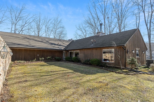 back of house featuring central AC, a chimney, and a lawn