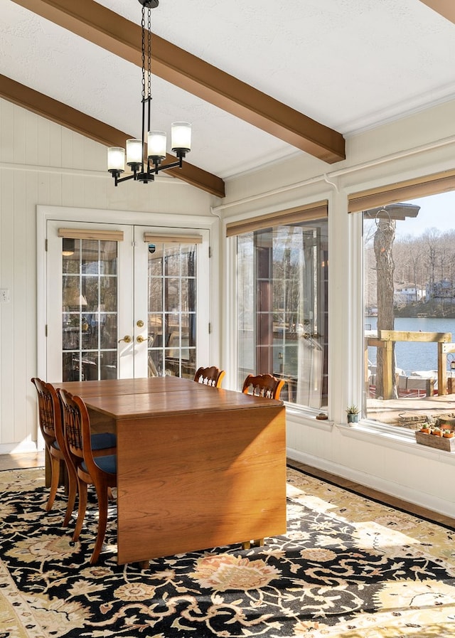 interior space featuring french doors, a notable chandelier, a water view, lofted ceiling with beams, and wood finished floors