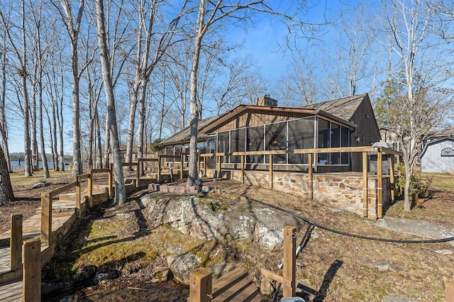 view of side of home featuring a sunroom and a chimney