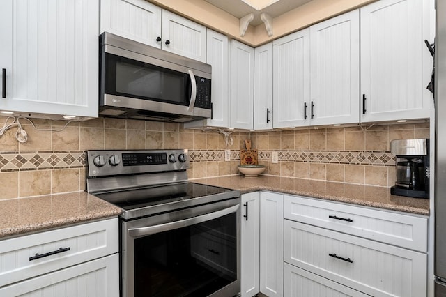 kitchen with appliances with stainless steel finishes, white cabinets, decorative backsplash, and light stone countertops