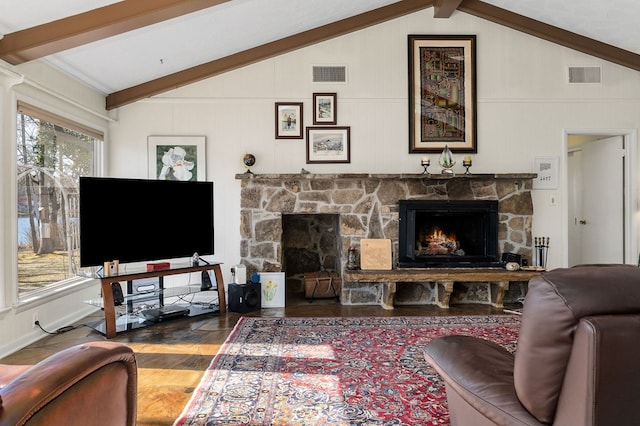 living room featuring visible vents, vaulted ceiling with beams, a stone fireplace, and wood finished floors