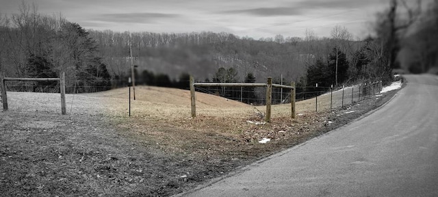 exterior space featuring a forest view, fence, and volleyball court