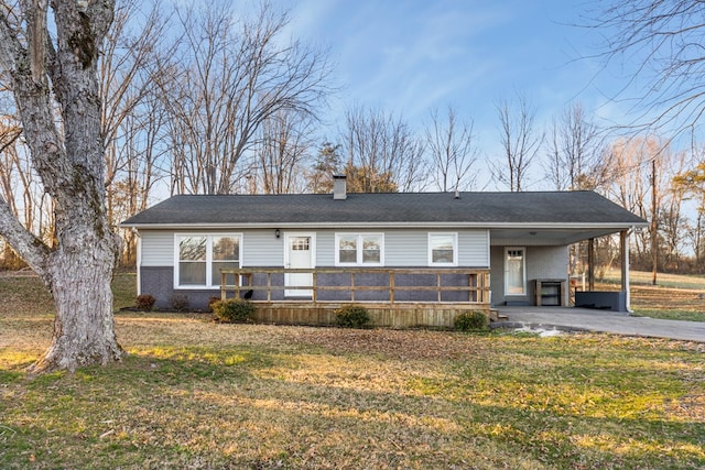 view of front facade with brick siding, a chimney, a front yard, an attached carport, and driveway