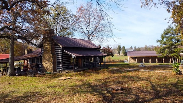 view of side of home with metal roof, a lawn, and a chimney