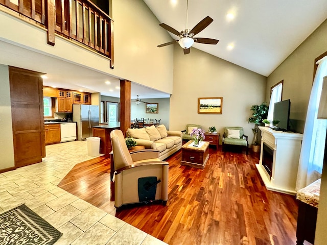 living area featuring ceiling fan, a fireplace, high vaulted ceiling, and wood finished floors