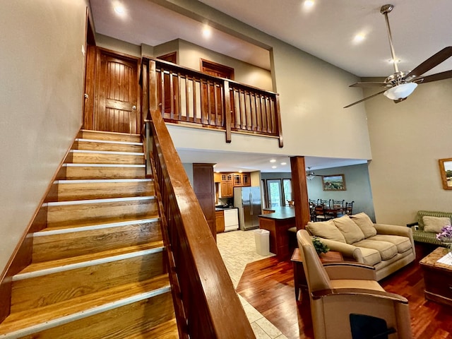 staircase with recessed lighting, ceiling fan, a towering ceiling, and wood finished floors