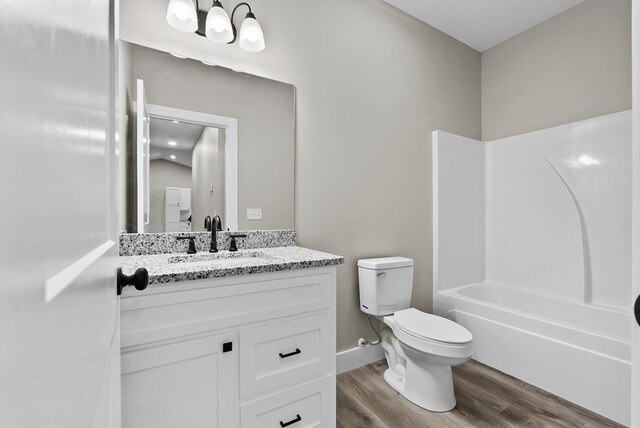 full bath with shower / tub combination, toilet, wood finished floors, vanity, and baseboards