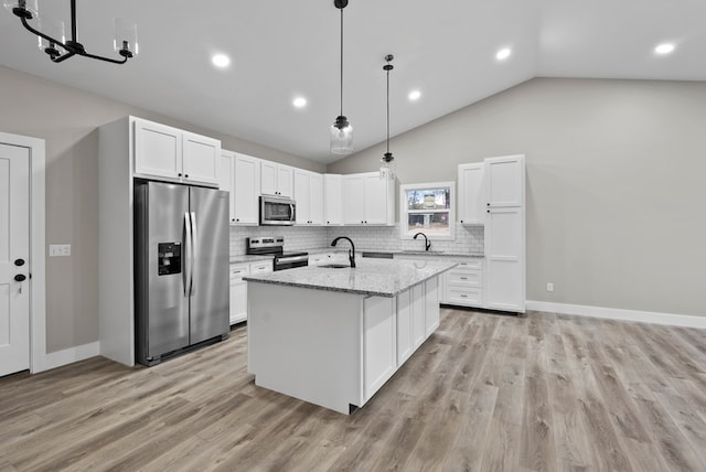 kitchen featuring light stone counters, a center island with sink, stainless steel appliances, white cabinetry, and a sink