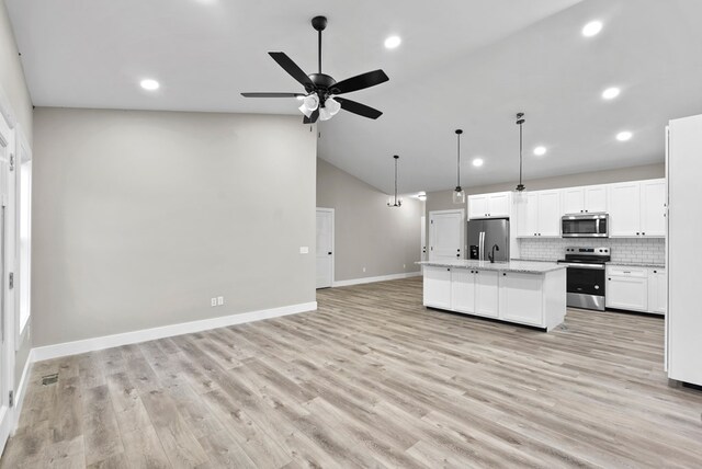 kitchen with open floor plan, a kitchen island with sink, stainless steel appliances, white cabinetry, and pendant lighting