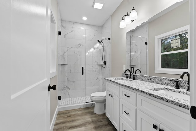 full bathroom with double vanity, a marble finish shower, a sink, and wood finished floors