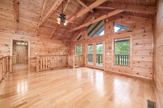 unfurnished room featuring light wood-style floors, visible vents, and wooden walls