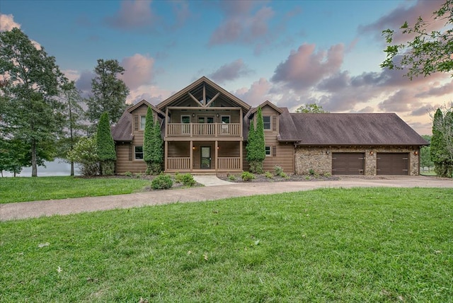 view of front of property with a balcony, an attached garage, a front lawn, and concrete driveway