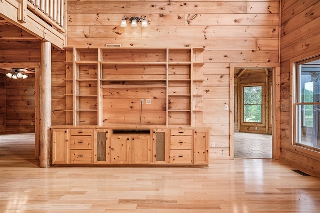 spare room featuring light wood-style flooring, wood walls, and visible vents