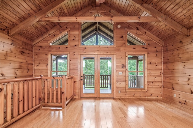 interior space featuring a wealth of natural light, light wood-type flooring, vaulted ceiling with beams, and wooden walls