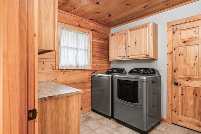 clothes washing area featuring wooden ceiling, washing machine and dryer, and cabinet space