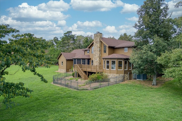 rear view of house featuring stairs, a chimney, a wooden deck, and a lawn