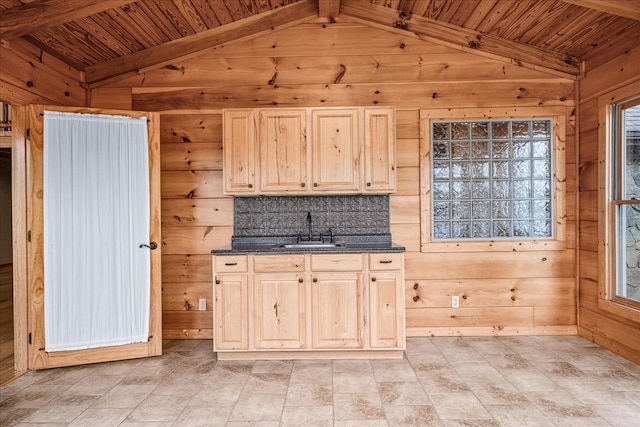 kitchen featuring light brown cabinets, wooden ceiling, a sink, and wooden walls