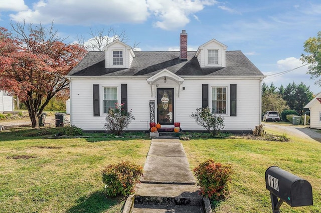 cape cod-style house with entry steps, a shingled roof, a chimney, and a front yard