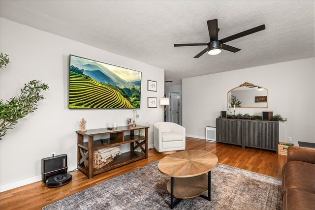 living room featuring ceiling fan, a textured ceiling, and wood finished floors