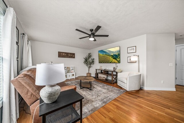 living room with baseboards, a textured ceiling, a ceiling fan, and wood finished floors