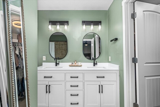 full bath with double vanity, a spacious closet, and a sink