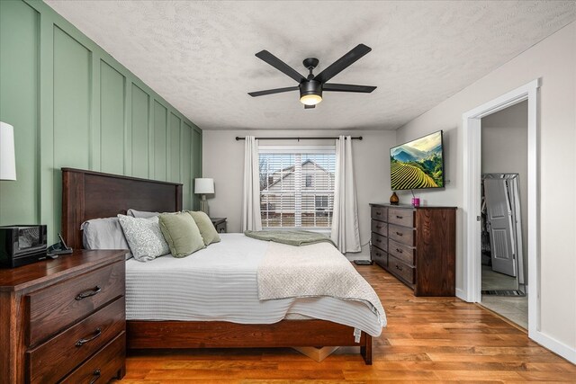 bedroom with a ceiling fan, a textured ceiling, and light wood finished floors