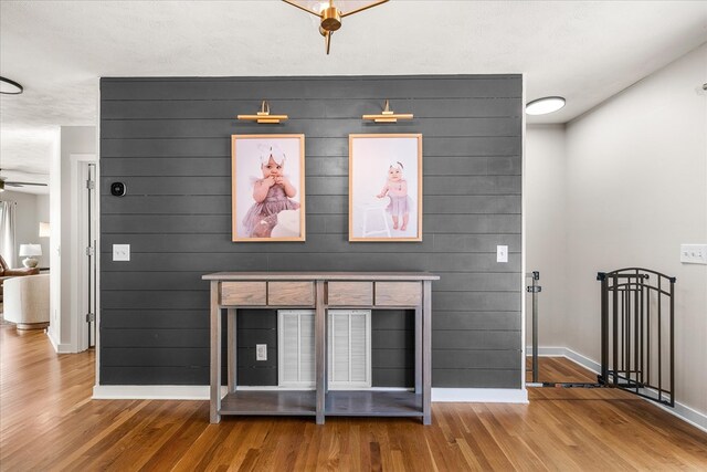 interior space featuring a ceiling fan, a textured ceiling, baseboards, and wood finished floors