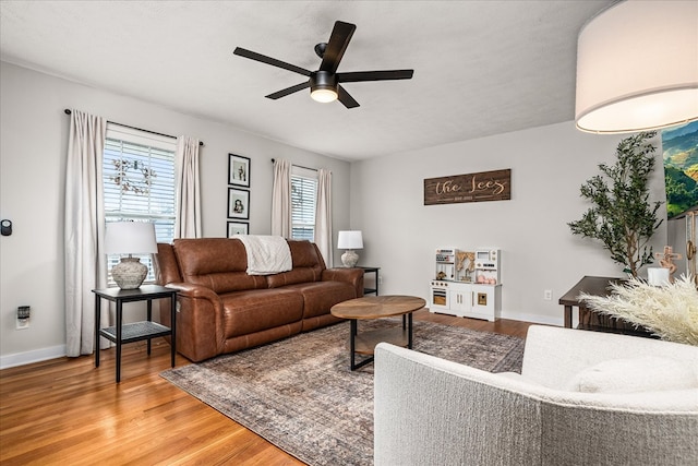 living room featuring a ceiling fan, a wealth of natural light, baseboards, and wood finished floors