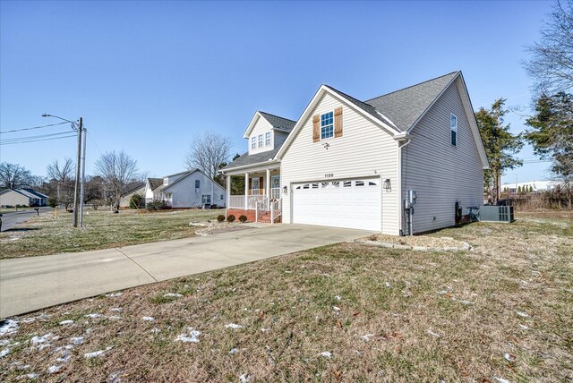 view of front of house with covered porch, central AC, a garage, driveway, and a front yard