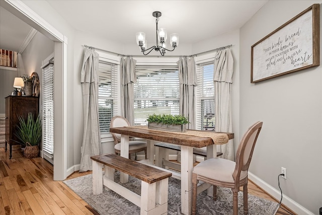 dining room featuring light wood-type flooring, baseboards, and a notable chandelier