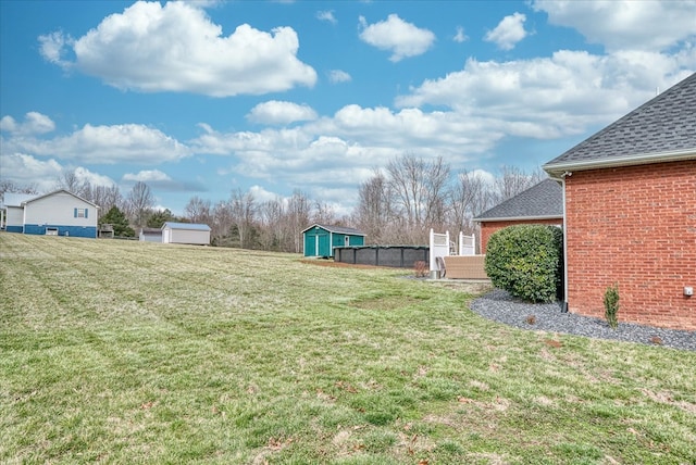 view of yard featuring a storage unit, an outdoor structure, and fence