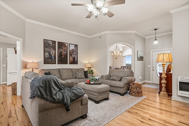 living room featuring arched walkways, ceiling fan with notable chandelier, light wood-style floors, heating unit, and crown molding