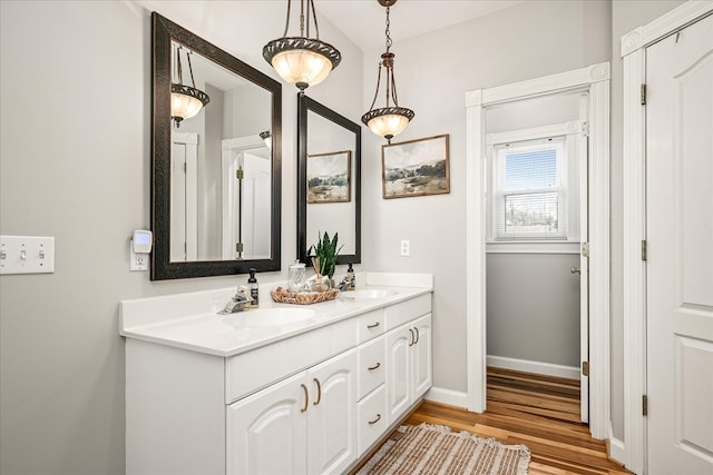 bathroom with double vanity, a sink, baseboards, and wood finished floors