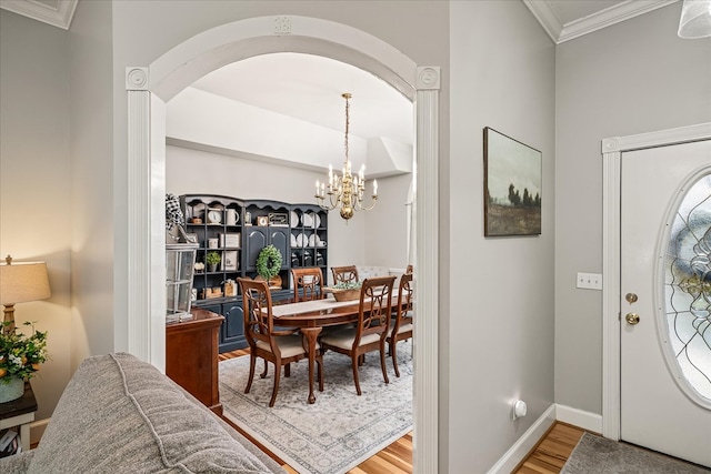 entryway featuring an inviting chandelier, baseboards, ornamental molding, and wood finished floors