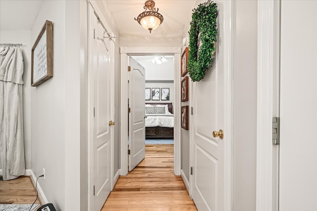 hall with light wood-style flooring and baseboards