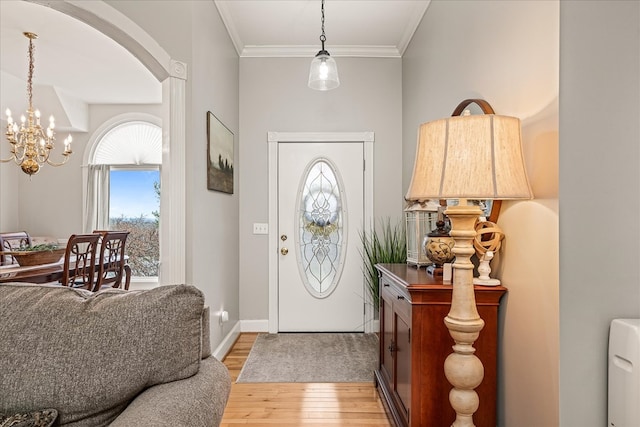 foyer featuring a chandelier, arched walkways, baseboards, light wood-style floors, and crown molding