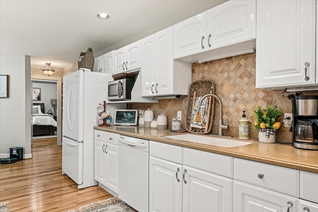 kitchen featuring light wood-type flooring, white appliances, white cabinets, and a sink