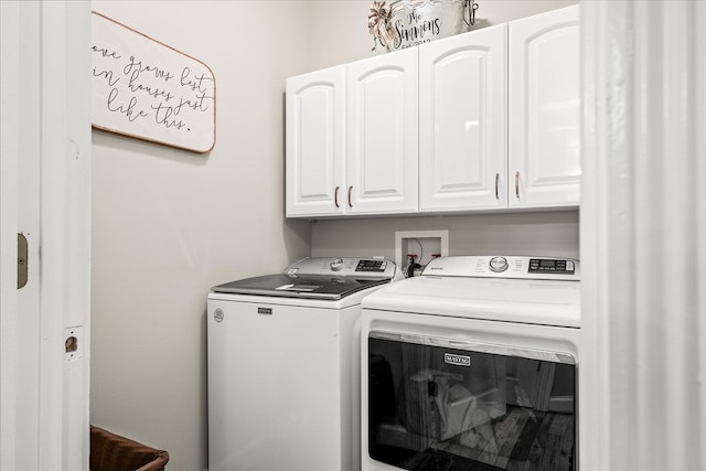 clothes washing area featuring cabinet space and washer and clothes dryer