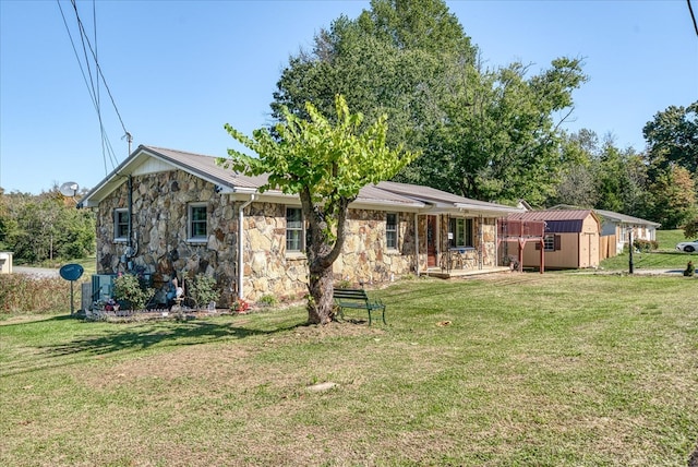 back of house featuring an outbuilding, a yard, a storage unit, central AC, and stone siding