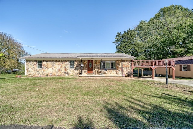 single story home featuring metal roof, stone siding, a front lawn, and a wooden deck