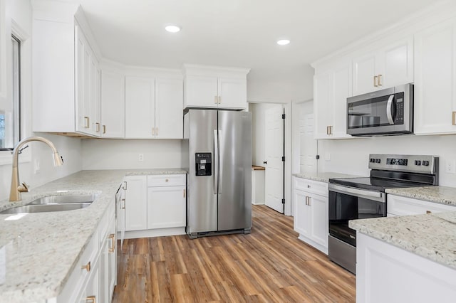 kitchen with recessed lighting, a sink, stainless steel appliances, white cabinets, and light wood-style floors